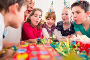 Child on birthday party blowing candles on cake